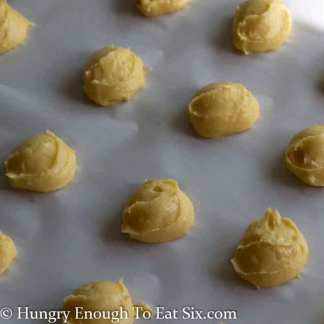 Mounds of choux dough on a baking sheet.
