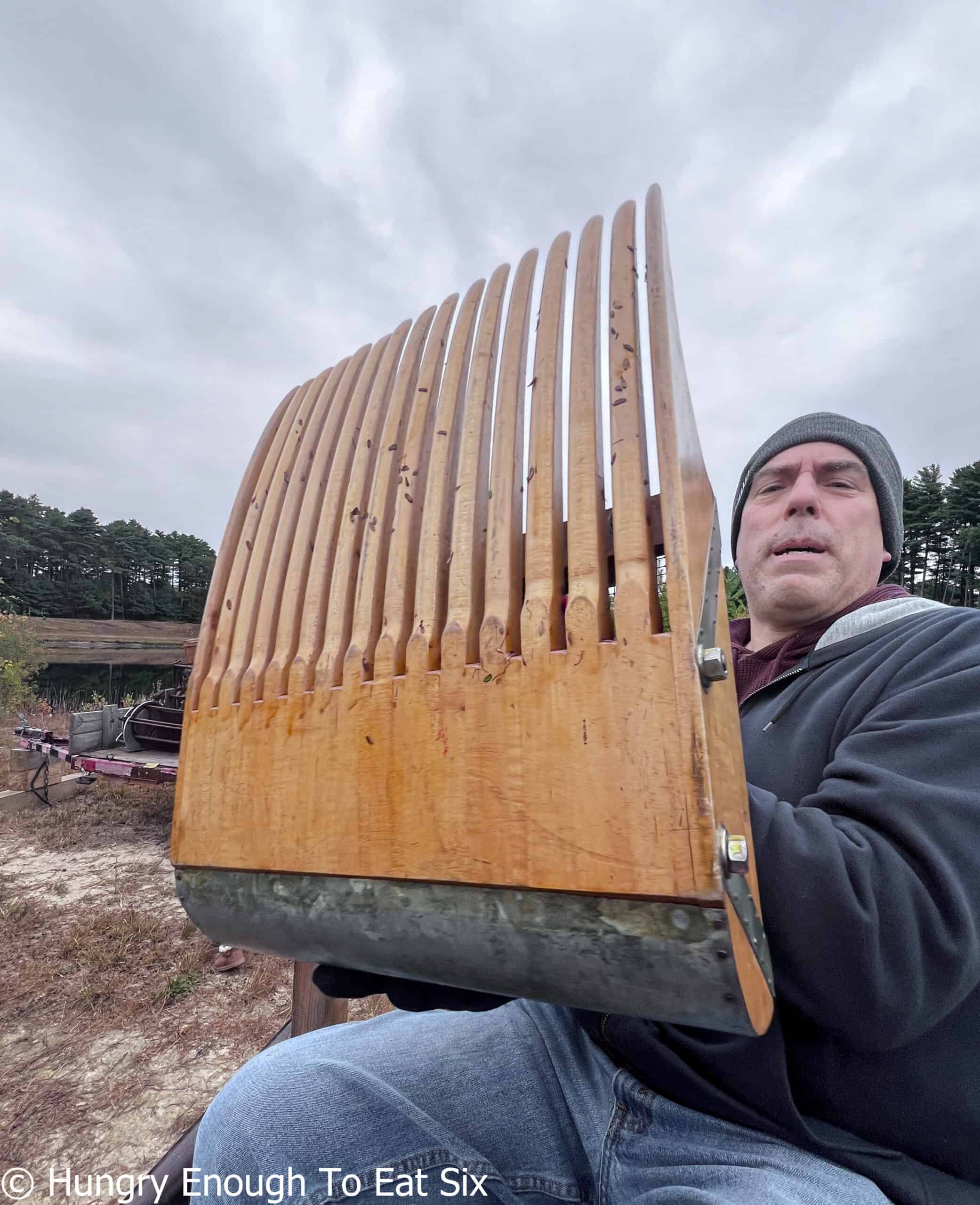 Man holding large wooden cranberry rake.