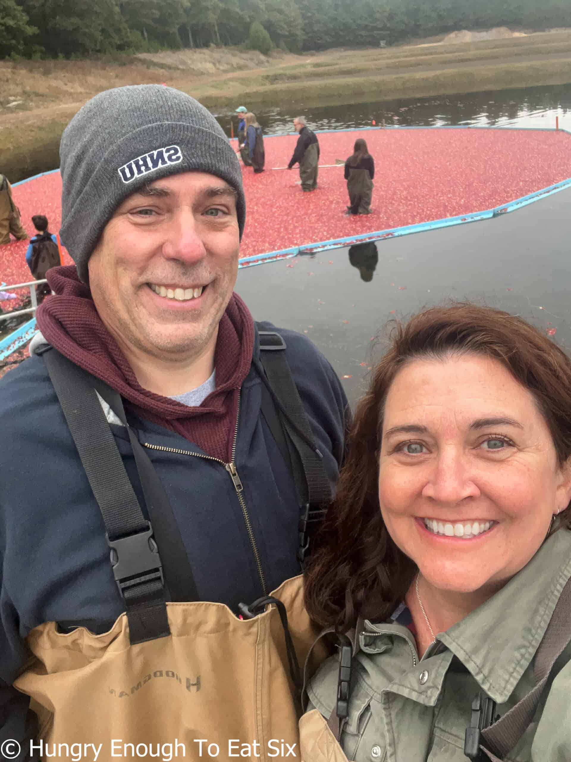 Smiling man and woman with cranberry bog in background.