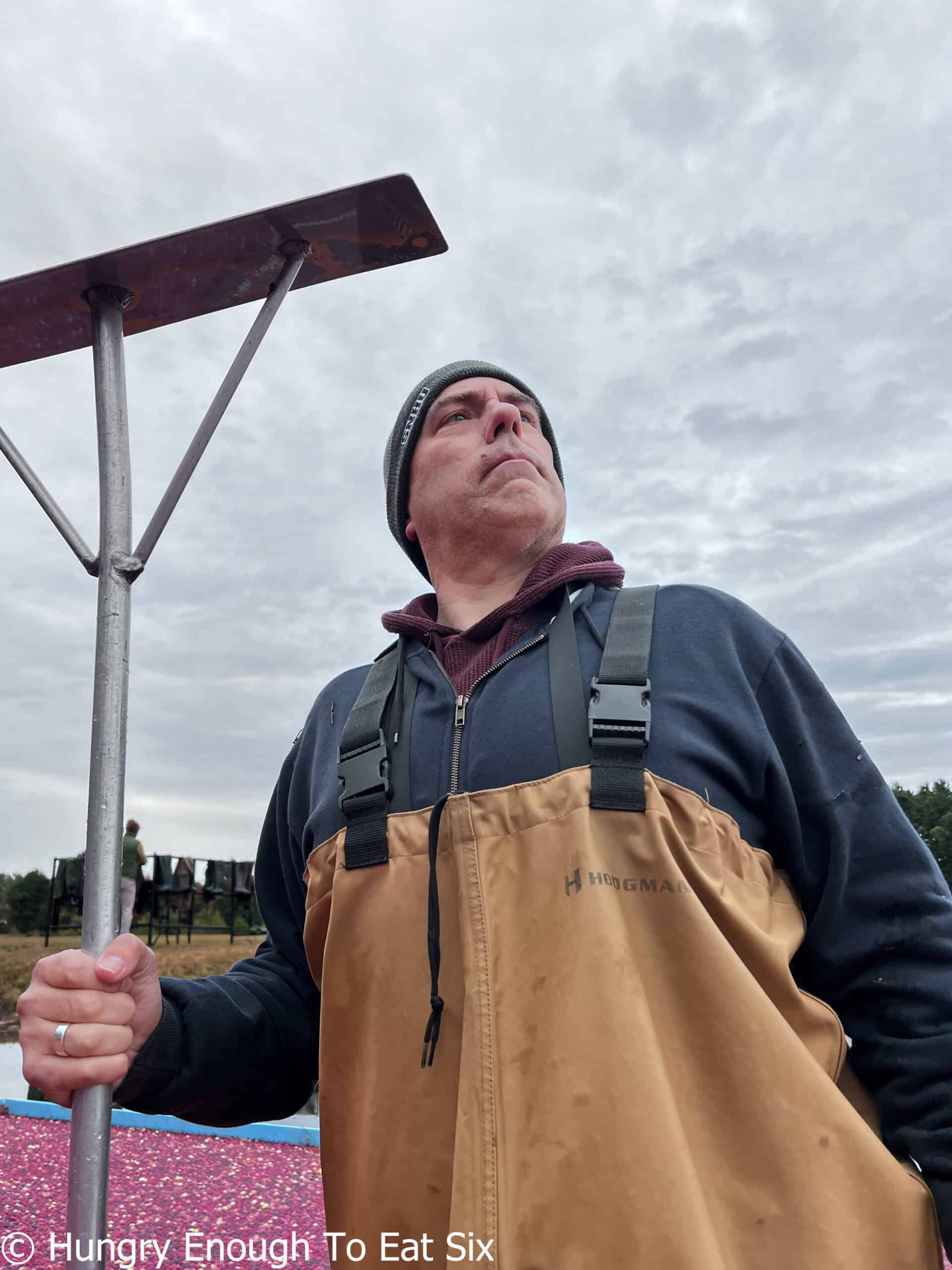 Man with rake looking at sky.