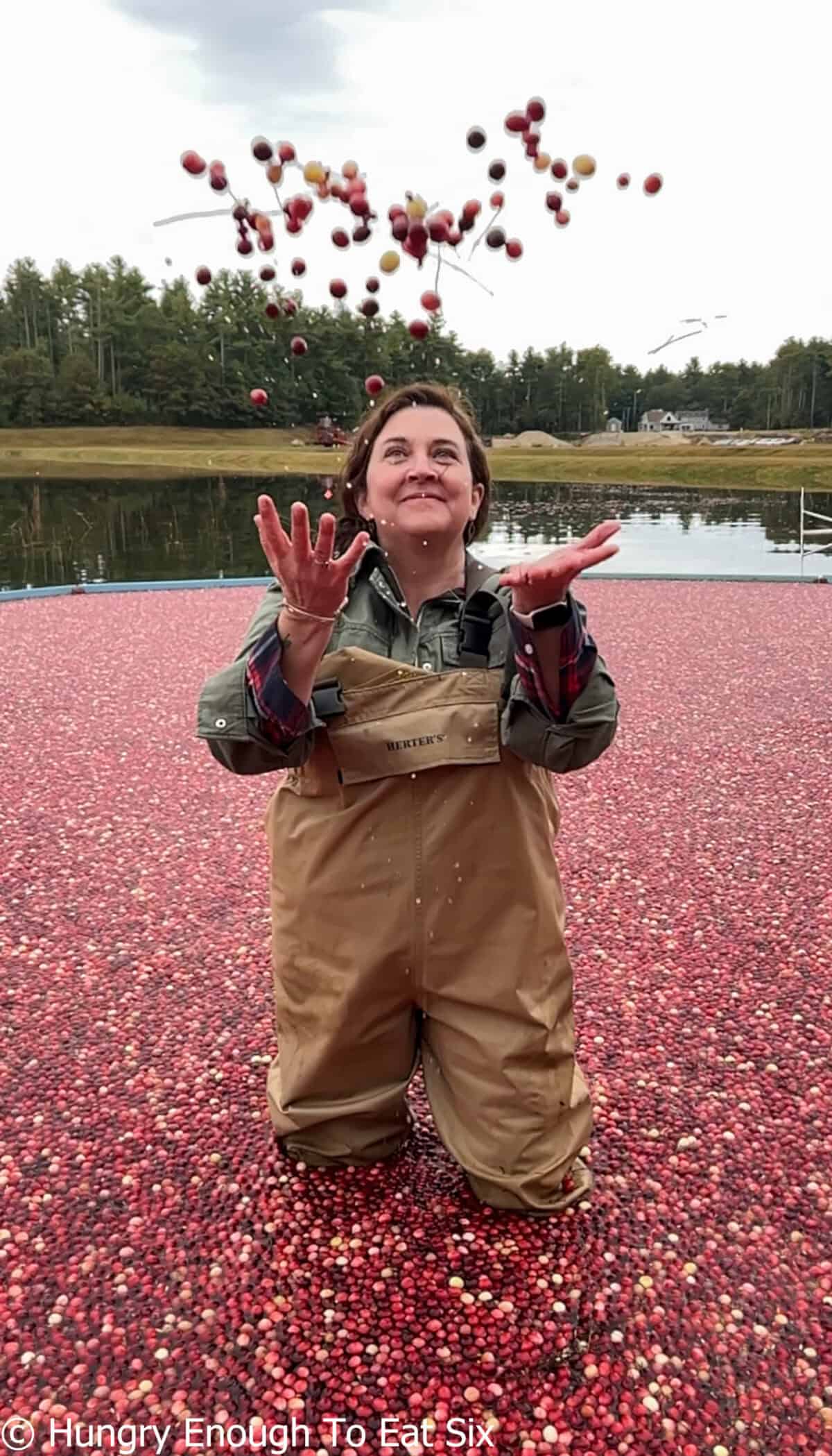 Woman with hands outstretched to catch falling berries.