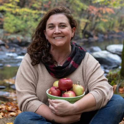Head shot of woman holding bowl of apples.