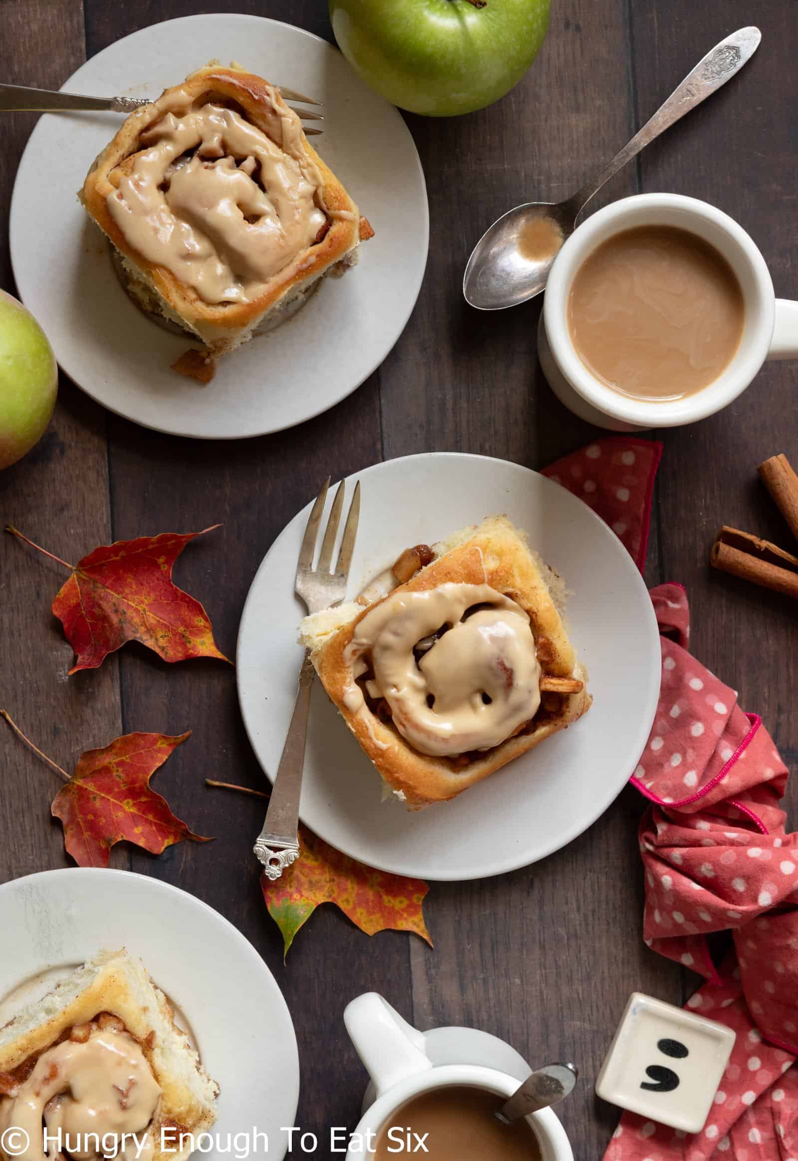 Iced cinnamon roll with cup of coffee nearby.