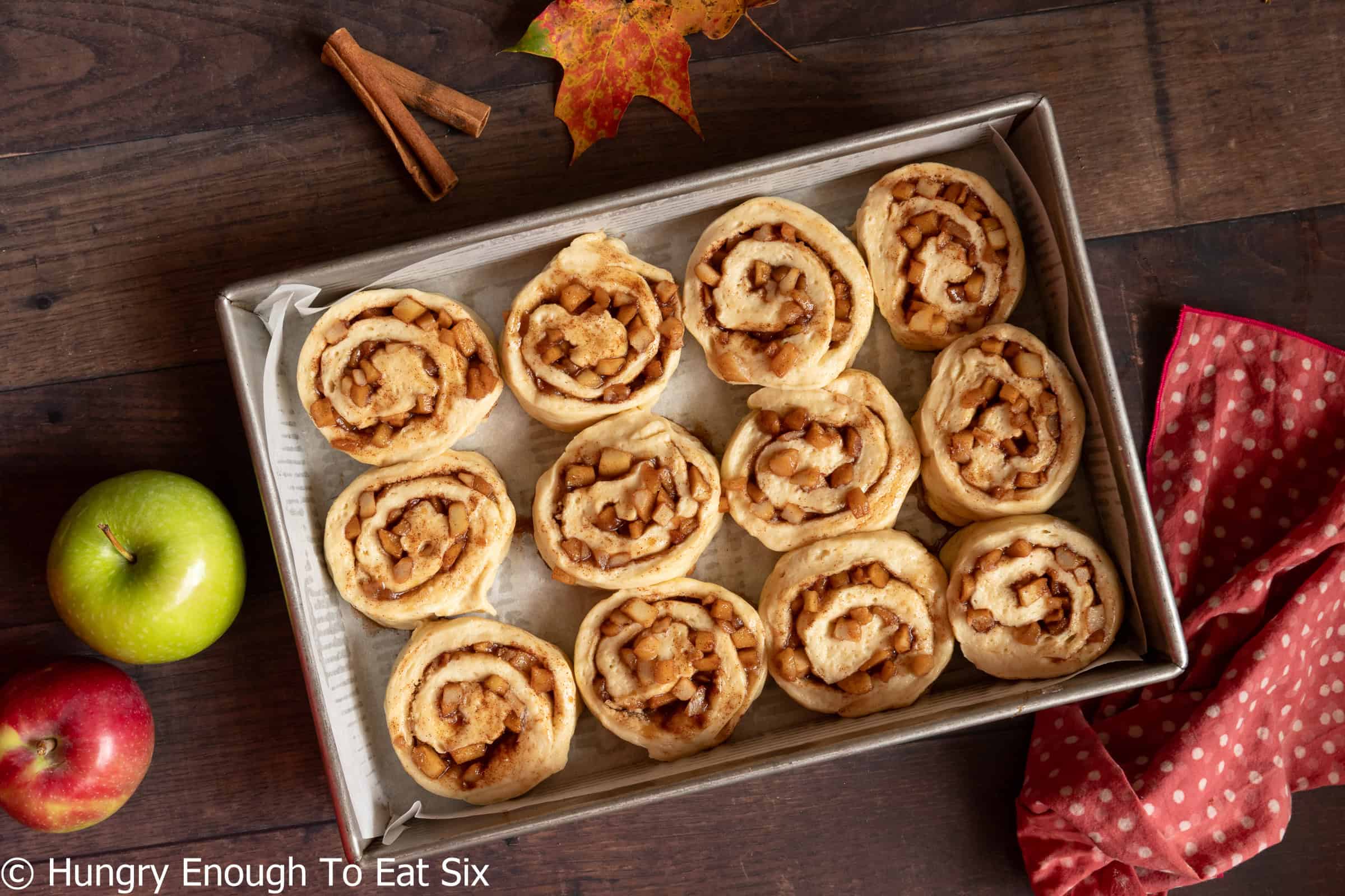 Twelve uncooked cinnamon rolls nestled into a baking pan.
