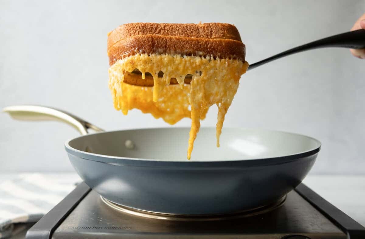 Grilled cheese on a spatula with melted cheese hanging down.