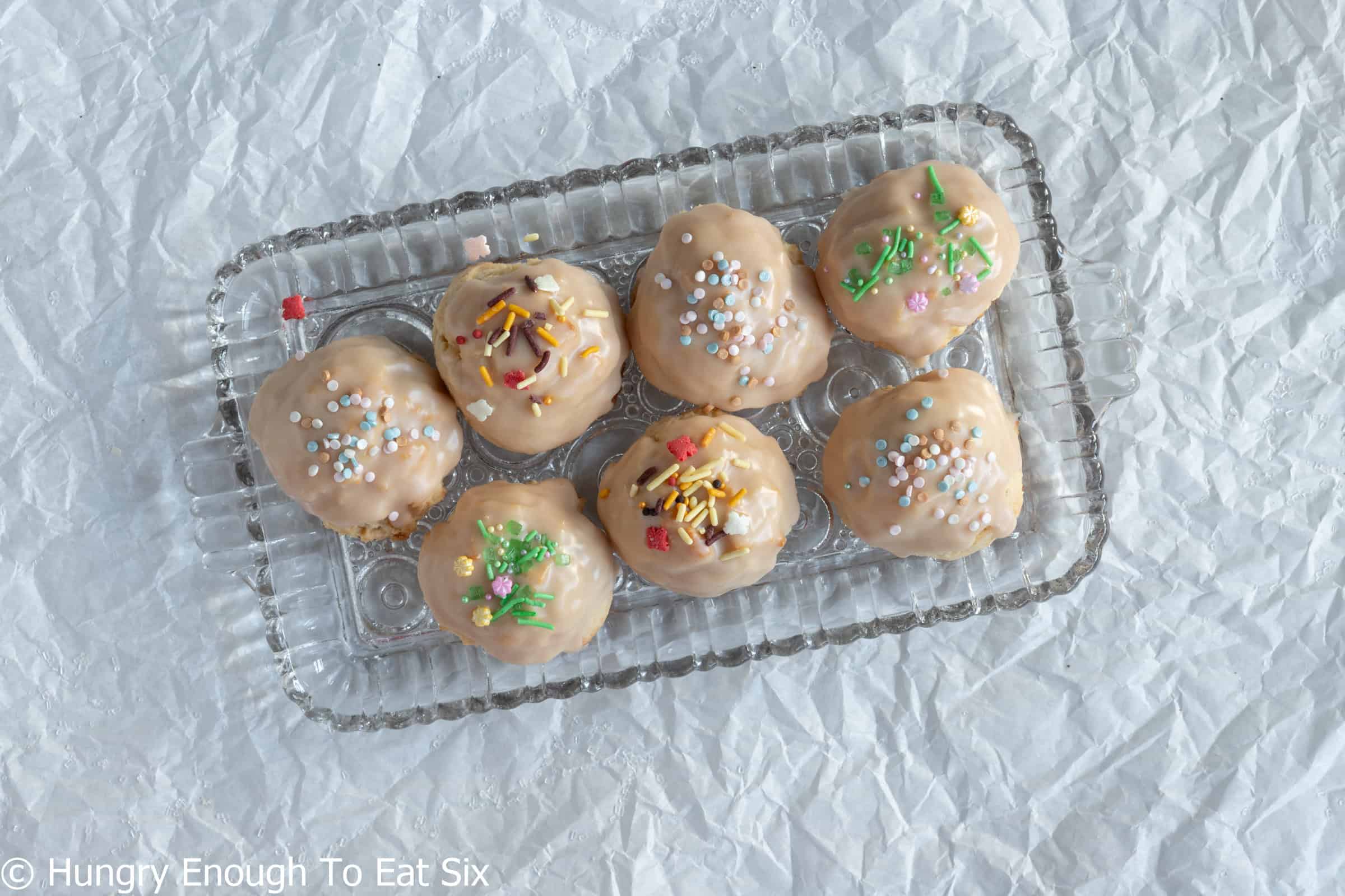 Glass plate with iced Vanilla Cozy-Ups cookies, sour cream sugar cookies.