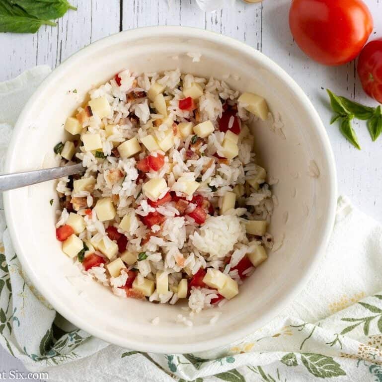 White bowl holding rice, tomato and cheese cubes