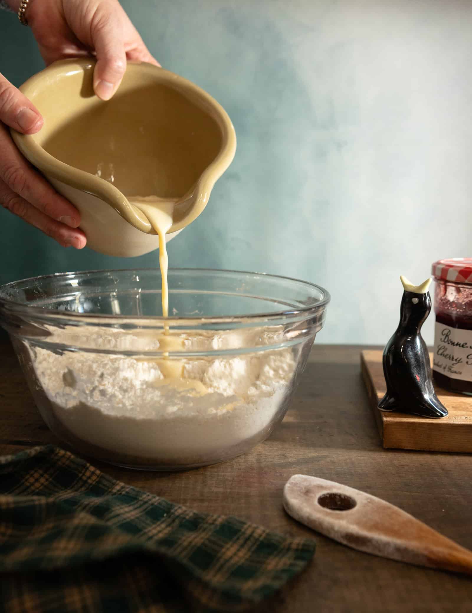 Hand pouring liquid mixture into dry ingredients for buttermilks scones.