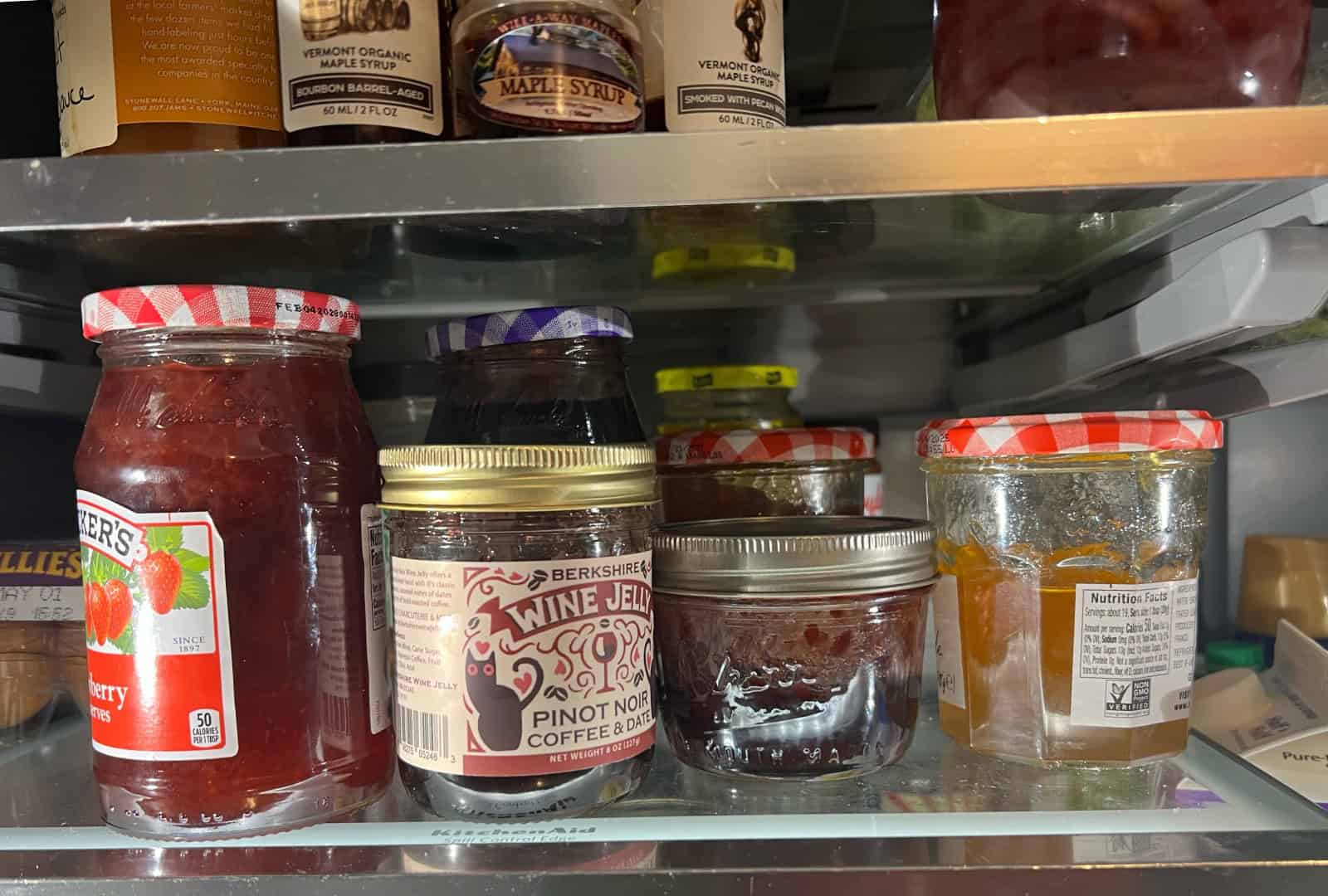 Refrigerator shelf with half-full jars of leftover jam.
