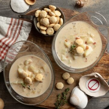 Two full bowls of New England no-clam chowder with crackers and shells.