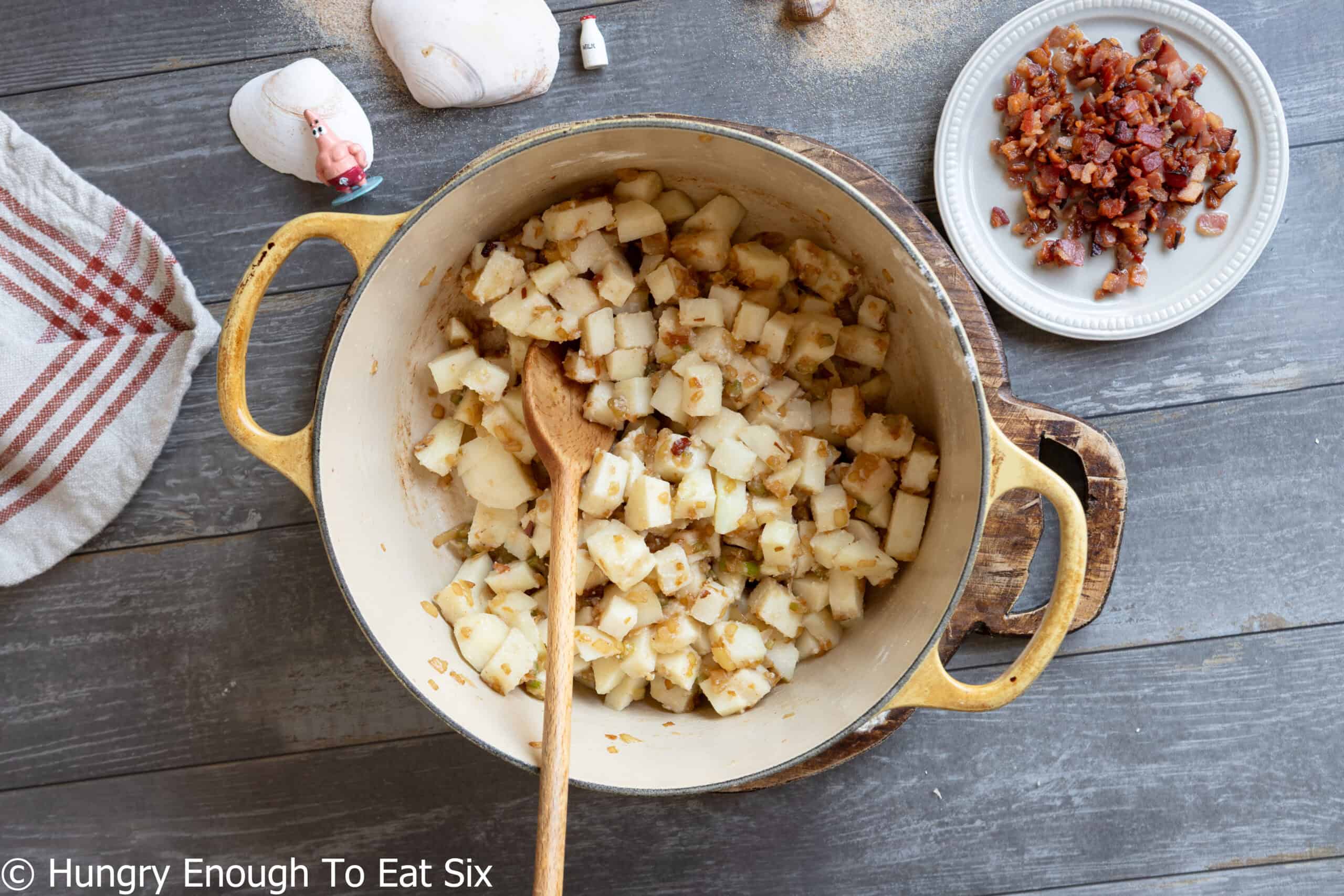 Diced potatoes with seasonings in a Dutch oven and ingredients to make no-clam chowder.