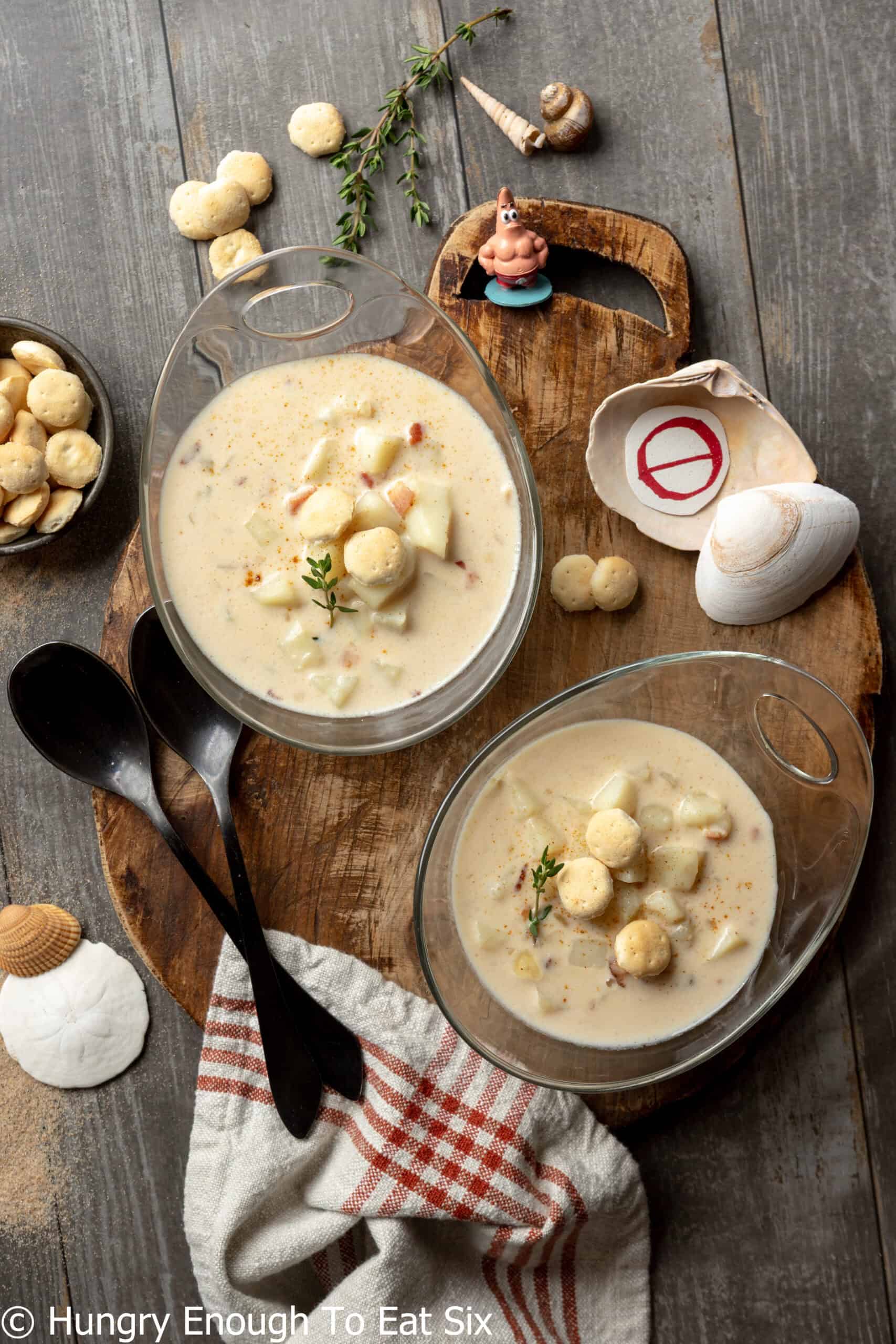 Bowls of New England no-clam chowder with black spoons and assorted shells.