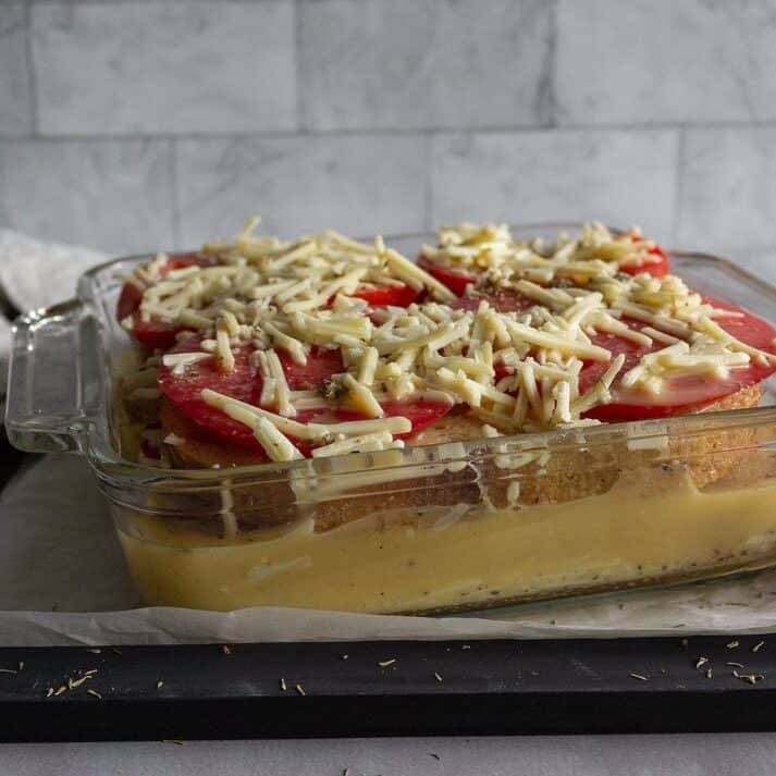 Layers of tomato, bread, and egg mixture in a baking dish