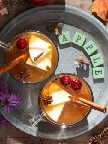Gray plate with cups of hot apple cider with spices.
