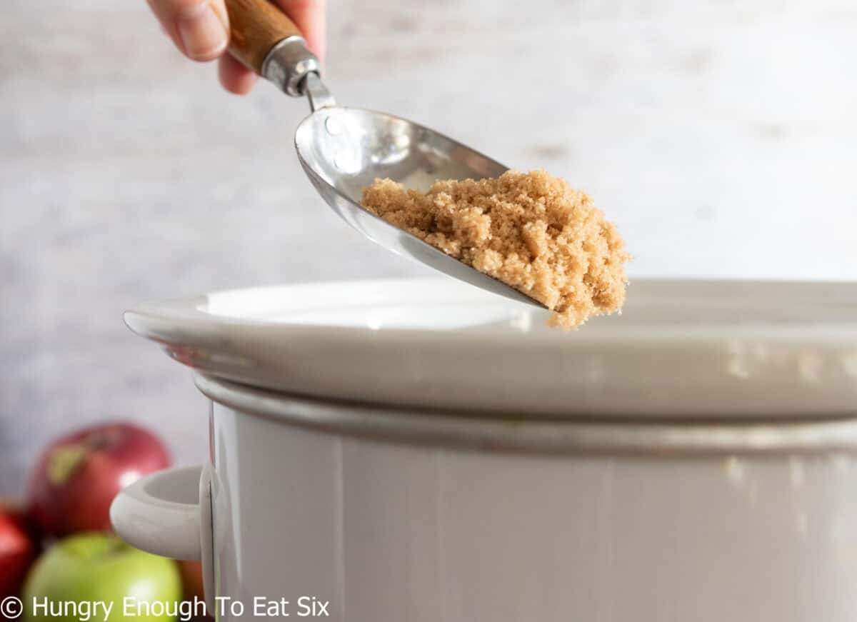 Brown sugar for hot apple cider pouring into a Crock Pot.