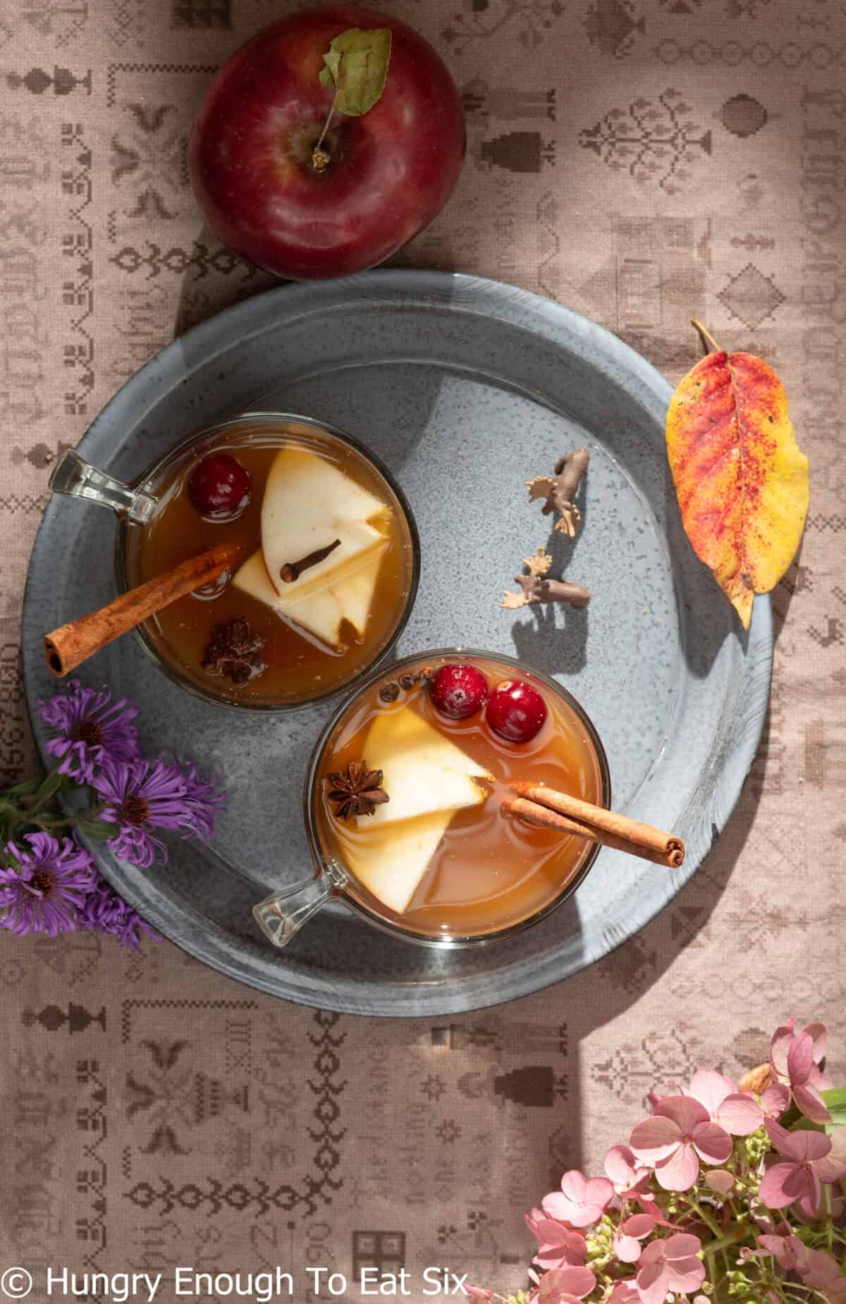 Cups of hot apple cider with cinnamon sticks.